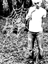 a man standing in the woods with a spider web
